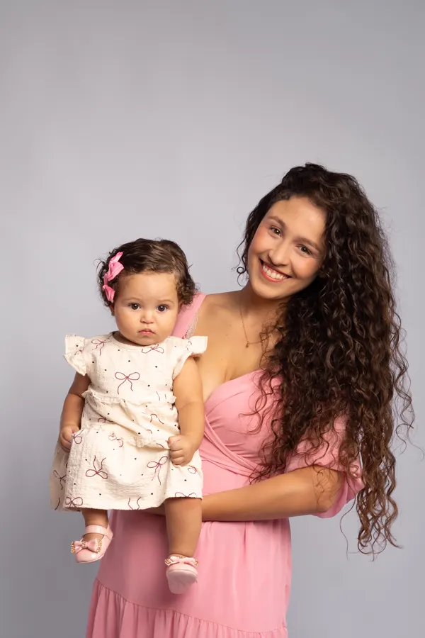 Mãe de vestido rosa com a bebê no colo