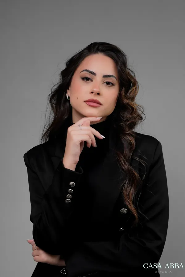 Retrato profissional em estúdio: mulher de blazer preto com mão no queixo