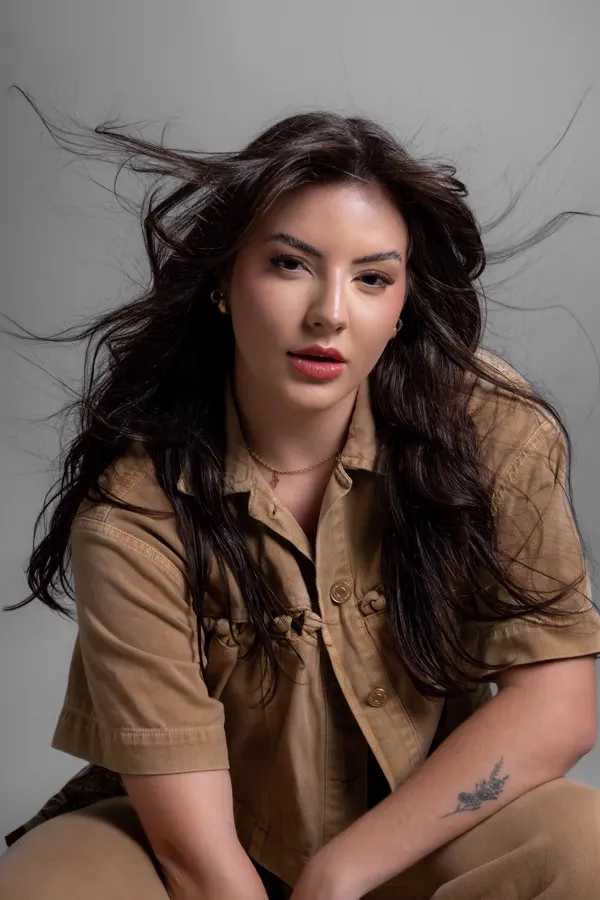 Retrato feminino com camisa caramelo e cabelo ao vento